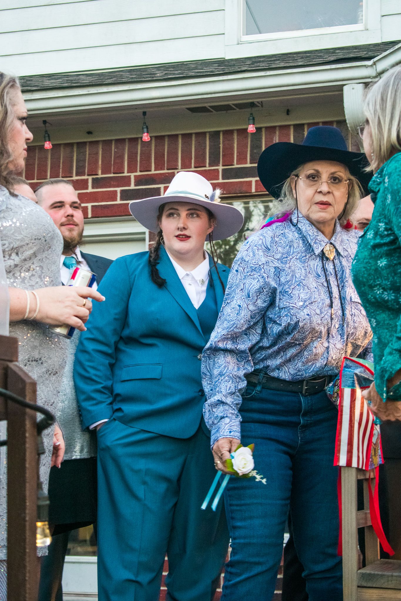 Group wearing western attire including cowboy hats and suits at an outdoor event.