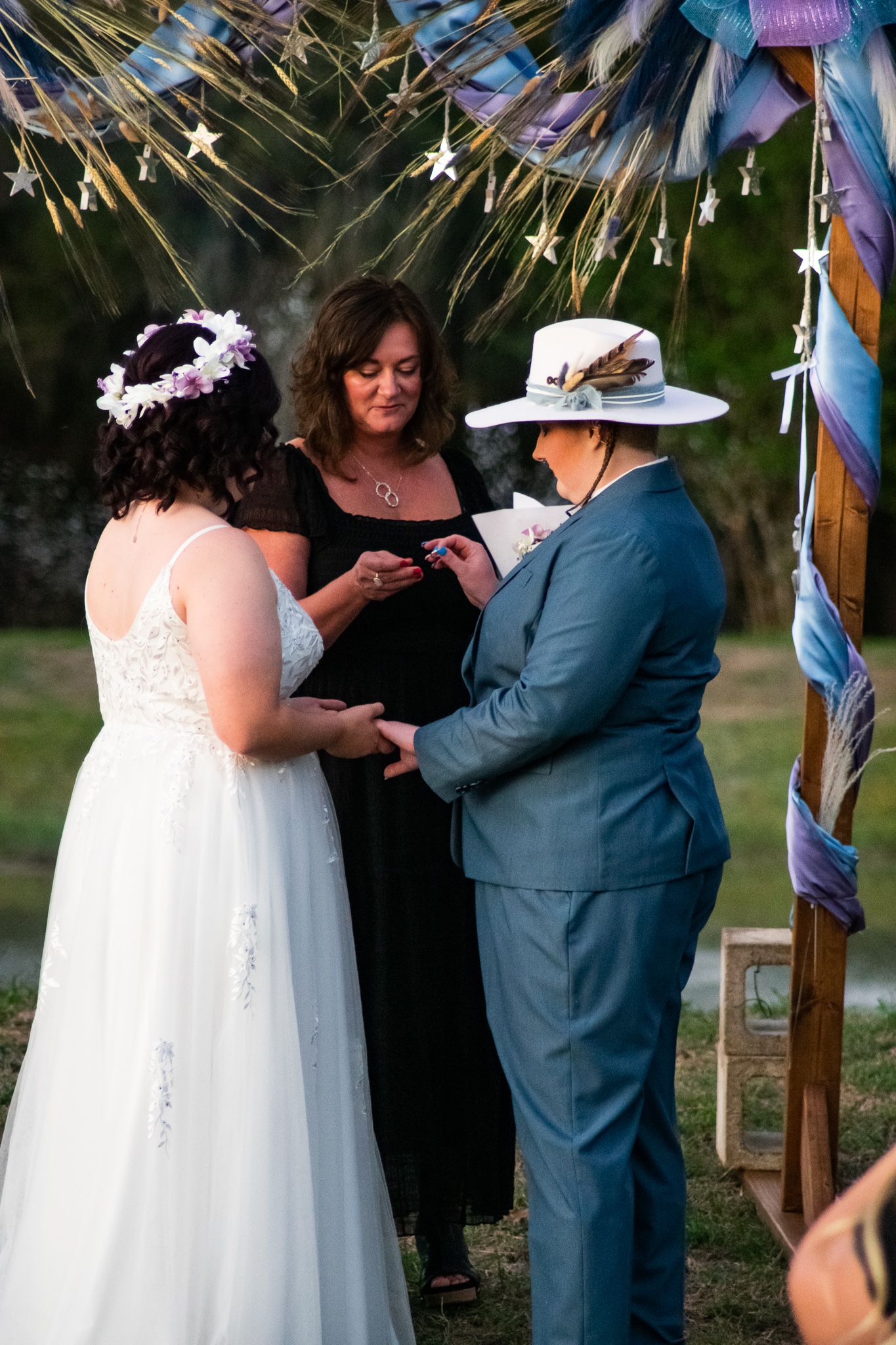 Wedding ceremony under twinkling lights with officiant conducting vows.