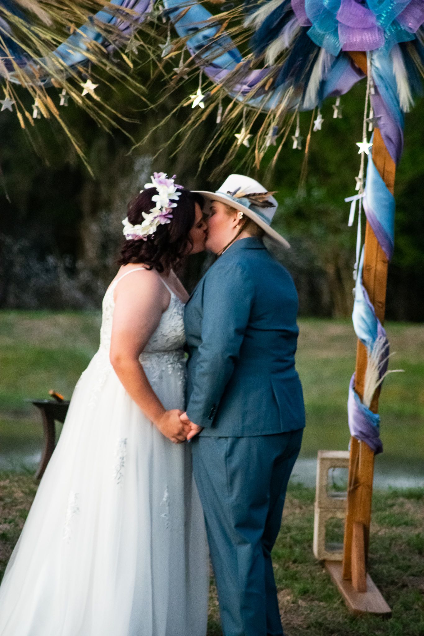 Couple shares first kiss during outdoor wedding ceremony beneath twinkling star decorations.