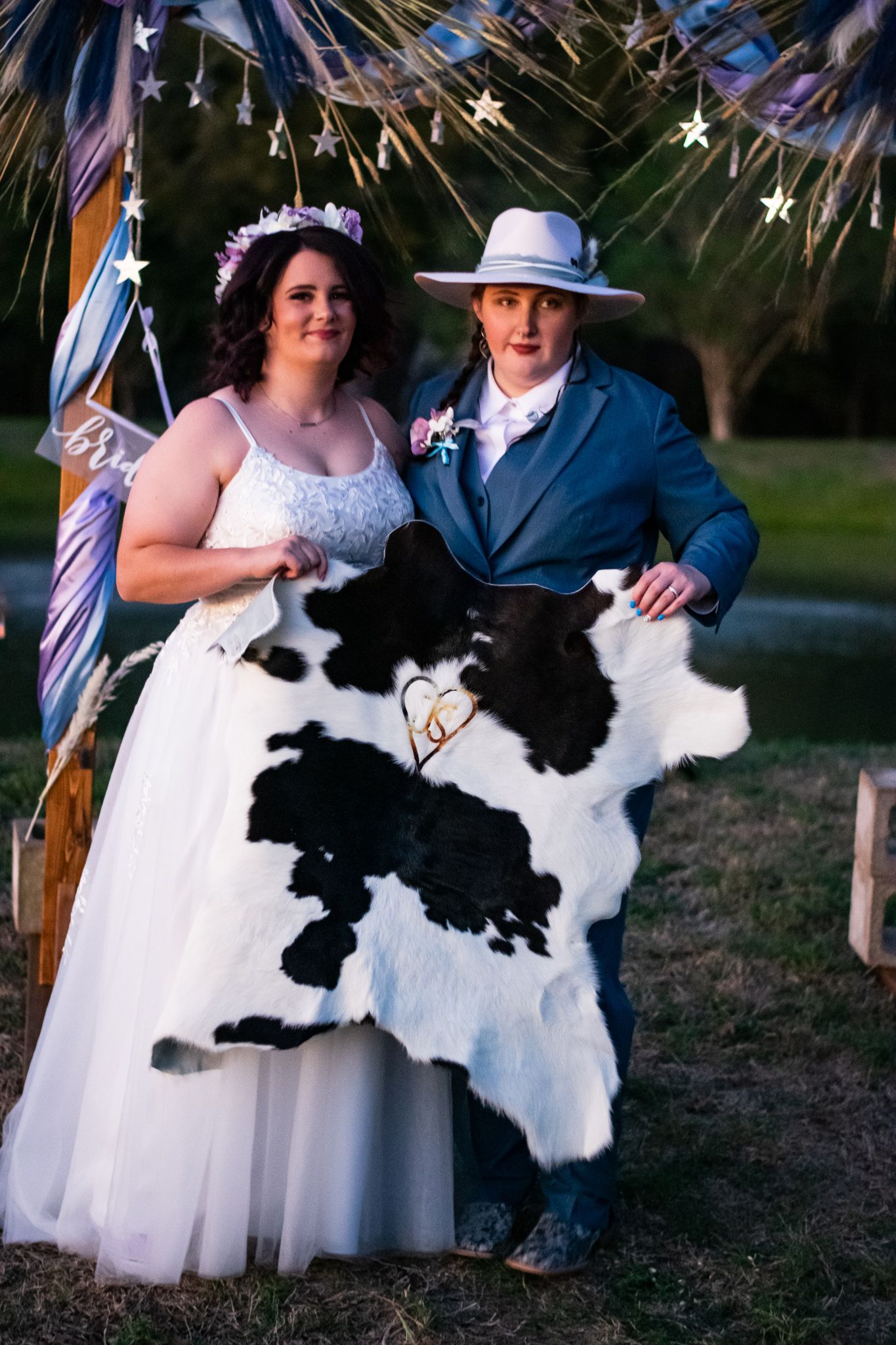 Wedding couple posing with a black and white cow hide under decorative stars.