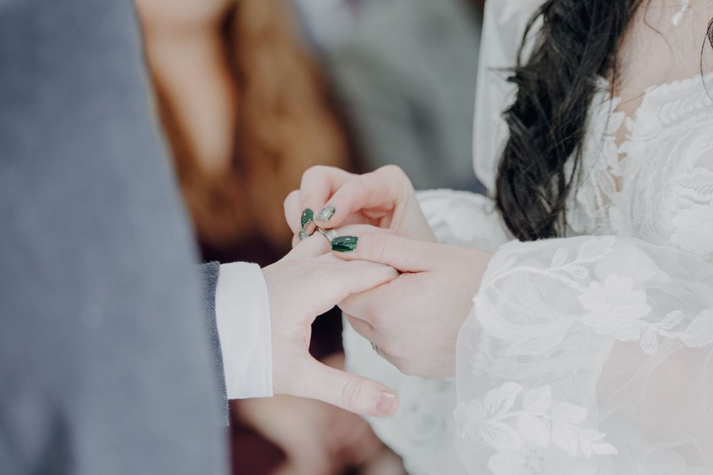 Close-up of hands exchanging rings during a wedding ceremony.