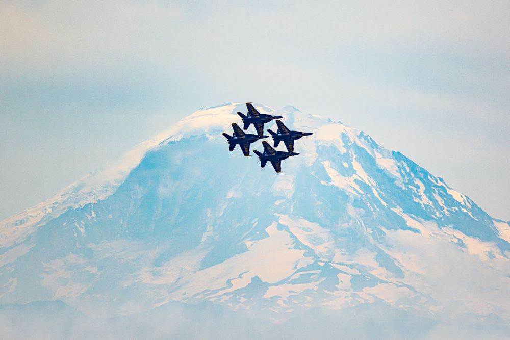 U.S. Navy Blue Angels in tight formation fly past snow-capped Mount Rainier in Washington state.