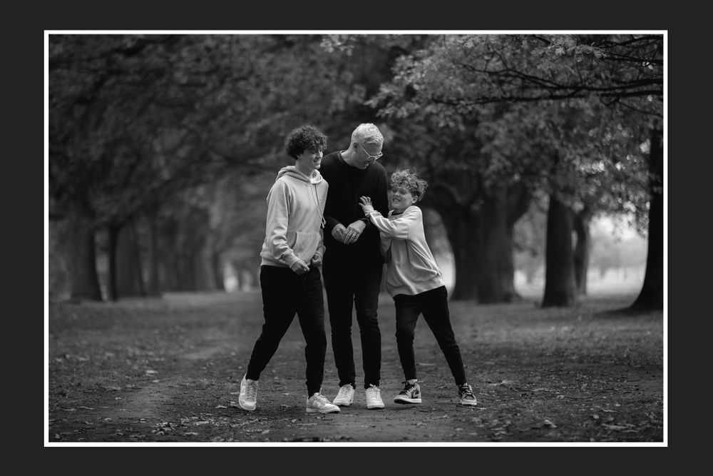 Black and white photo of three friends hugging in a misty autumn park.