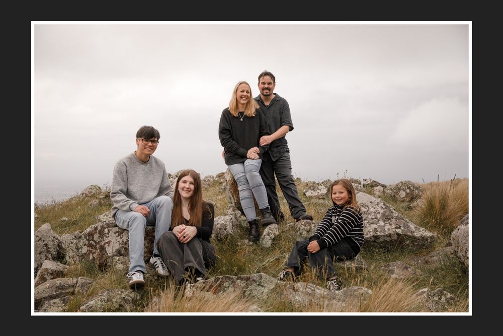 Group relaxing on rocky hillside with cloudy mountain backdrop.