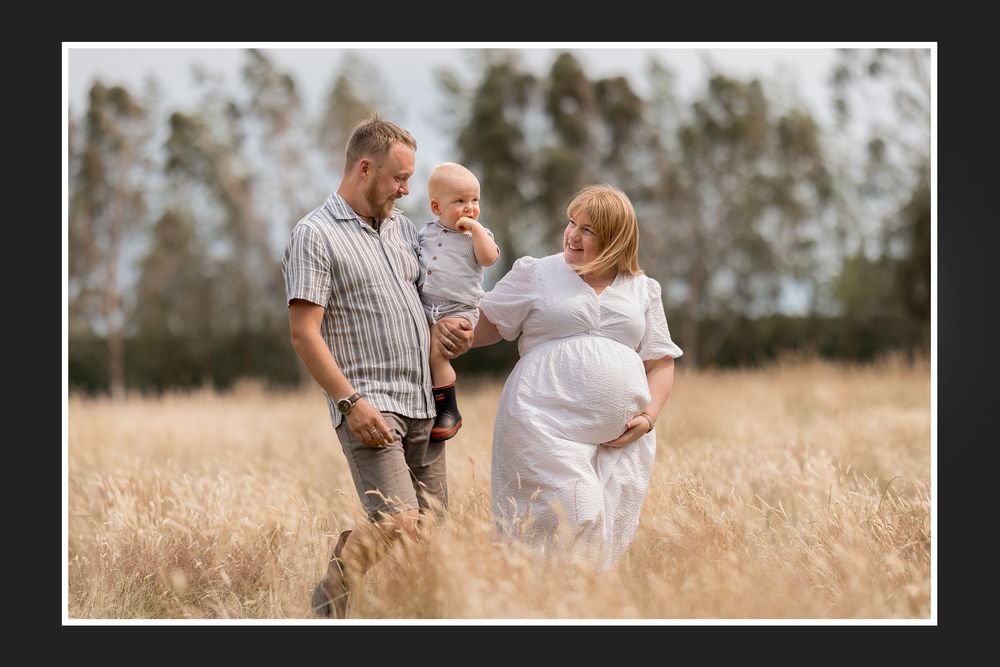 Family walking together through a golden wheat field at sunset during a summer photoshoot.