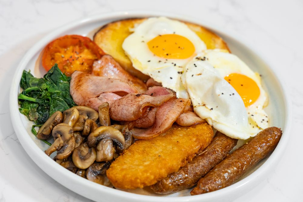 Full breakfast plate with eggs, bacon, mushrooms and hash browns.