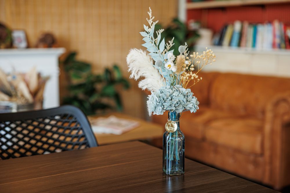 White floral arrangement in blue glass vase on wooden table.
