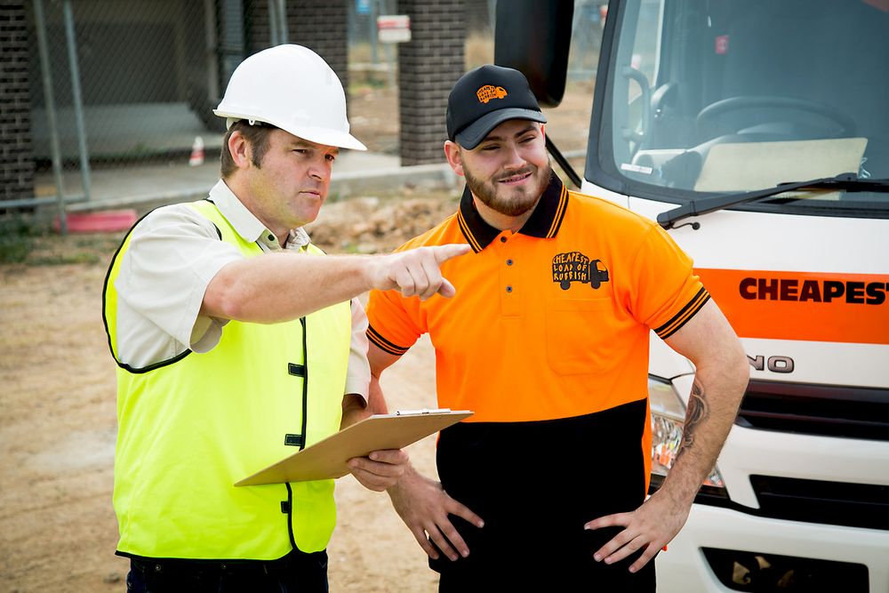 Two workers in high-visibility gear discuss operations next to a service vehicle.