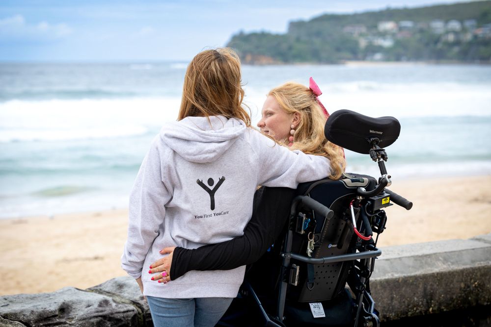 Two people share a joyful moment together on a scenic beach with waves in the background.