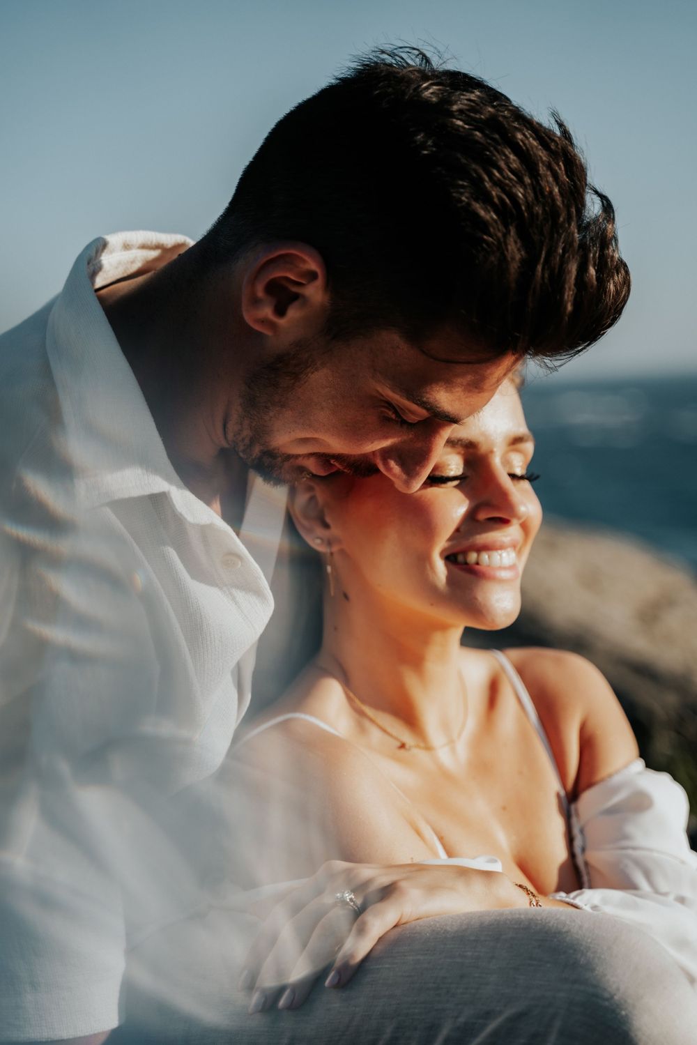 Intimate close-up portrait of couple sharing joyful moment by the ocean.