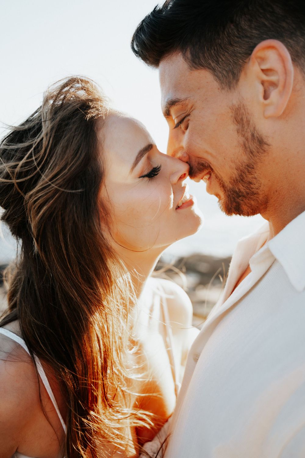 Intimate close-up of couple sharing tender moment in golden sunlight.
