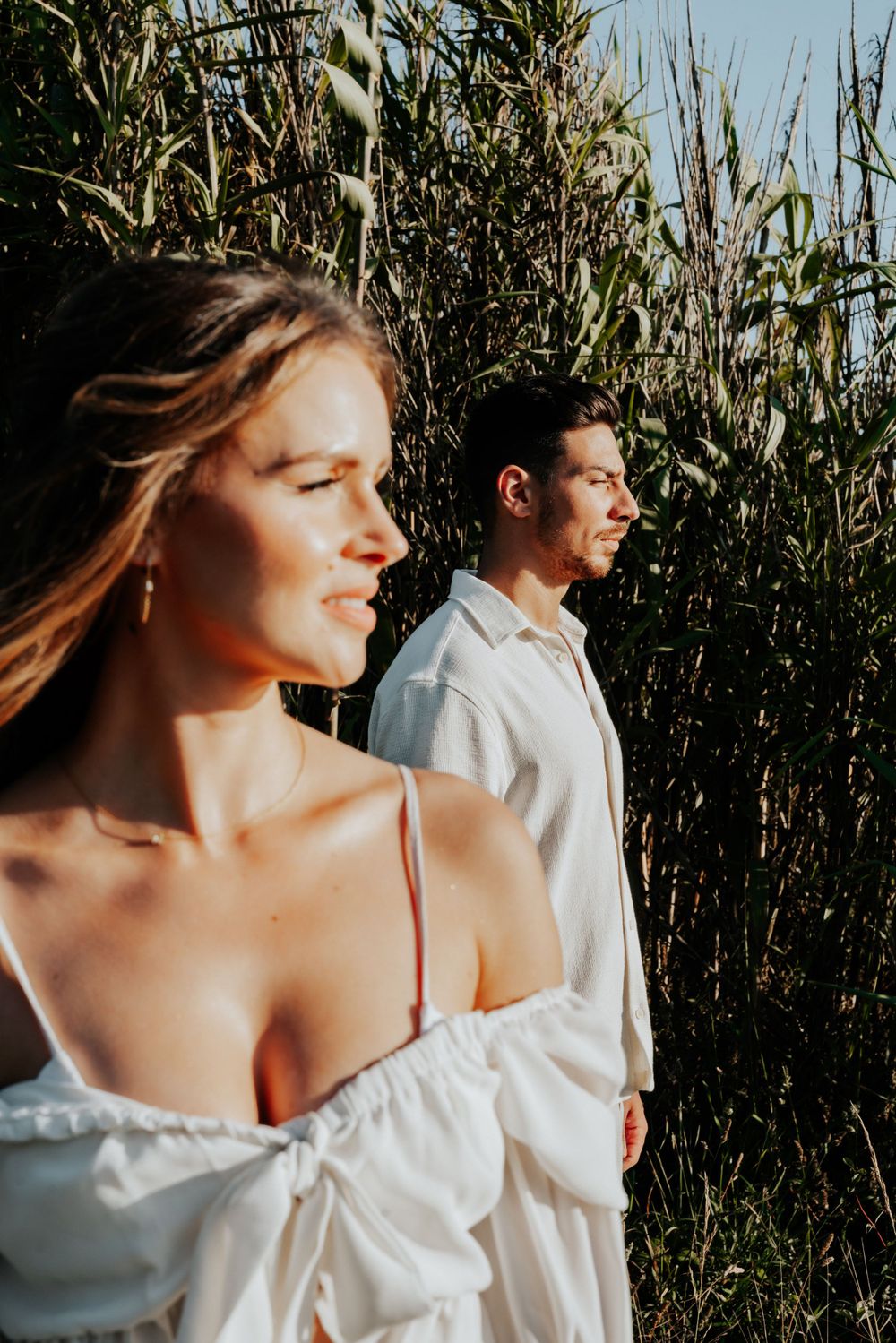 A dreamy summer portrait of a couple among tall grasses at golden hour.