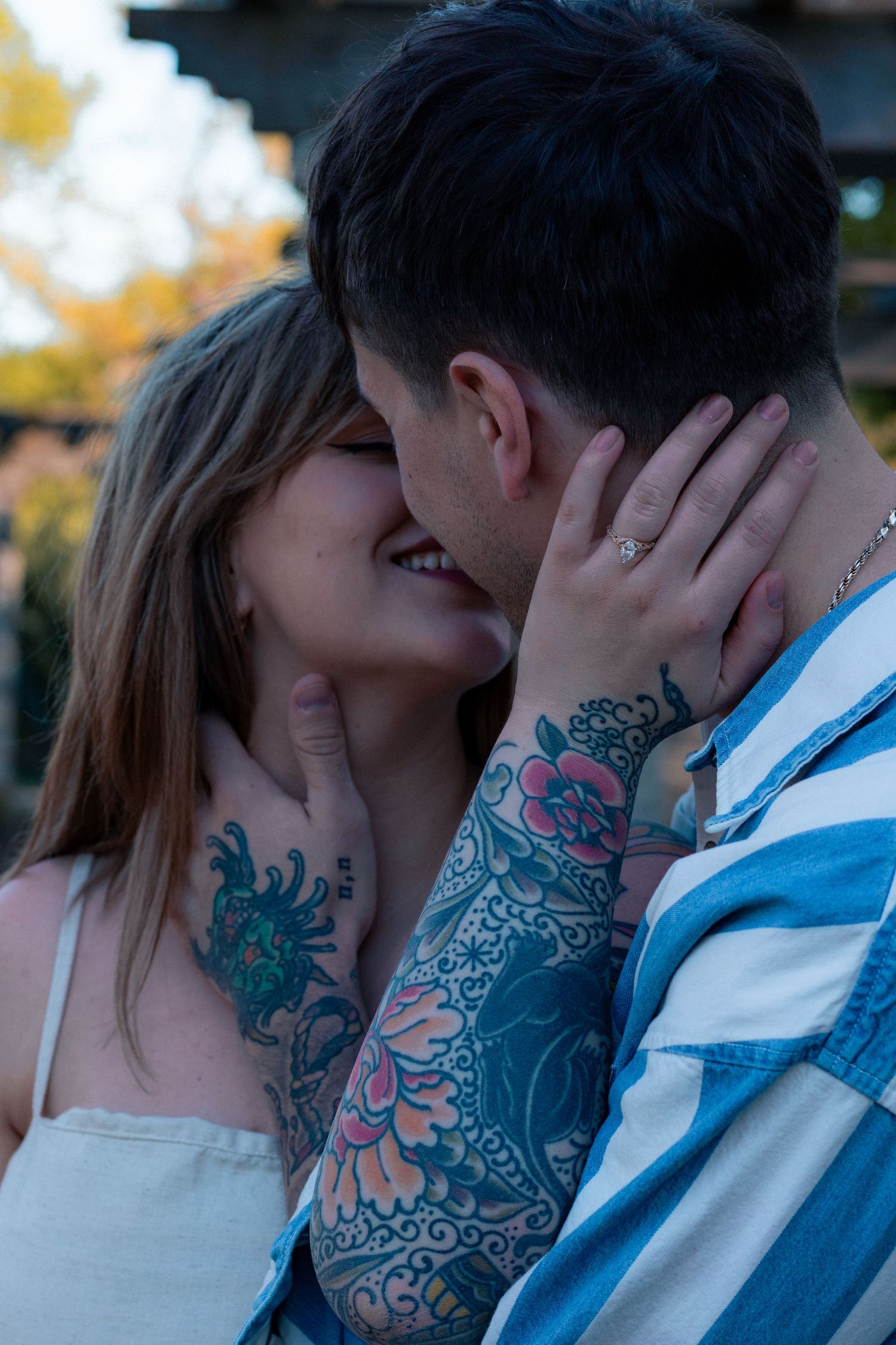 Couple sharing intimate moments outdoors with visible tattoos.