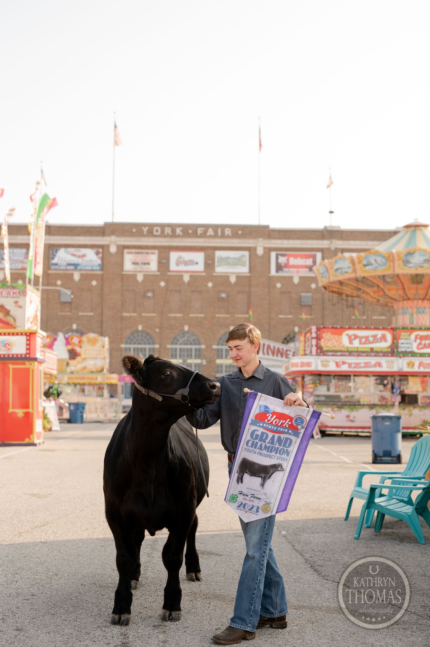 A champion livestock banner is displayed with black show animal at carnival fairgrounds.