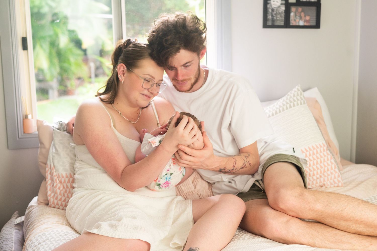 A tender family moment shared in a bright, sunlit bedroom.