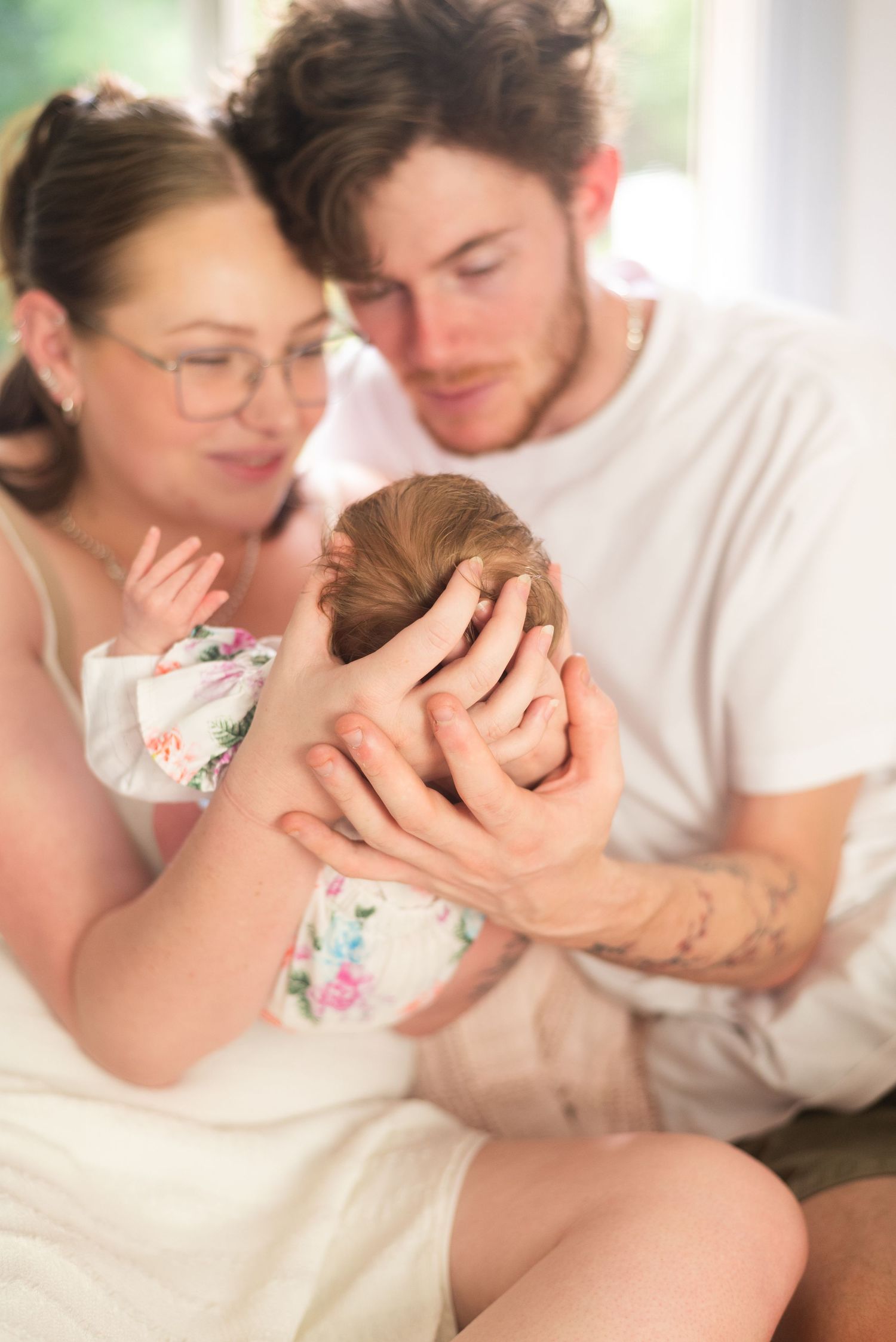 An intimate family portrait captured in soft natural window light.