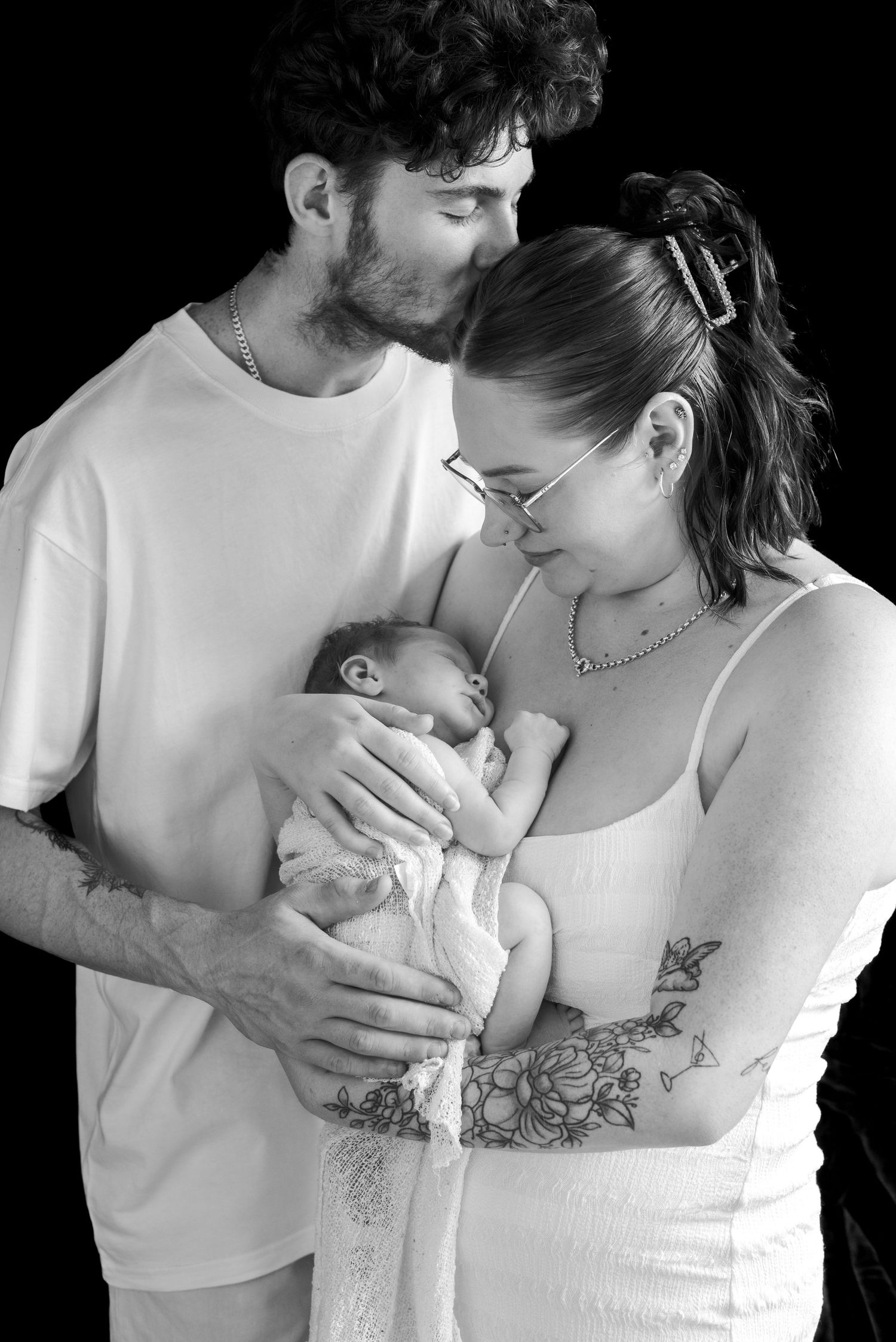A black and white intimate family portrait with soft lighting.
