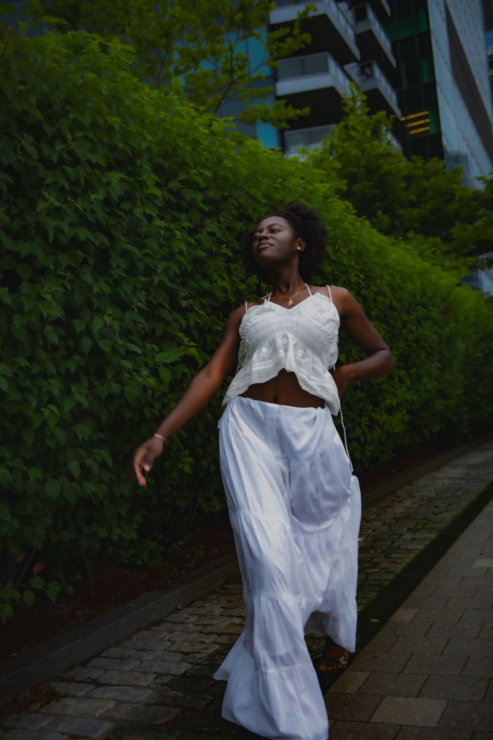 Elegant dance movement in white attire against urban greenery and architecture.