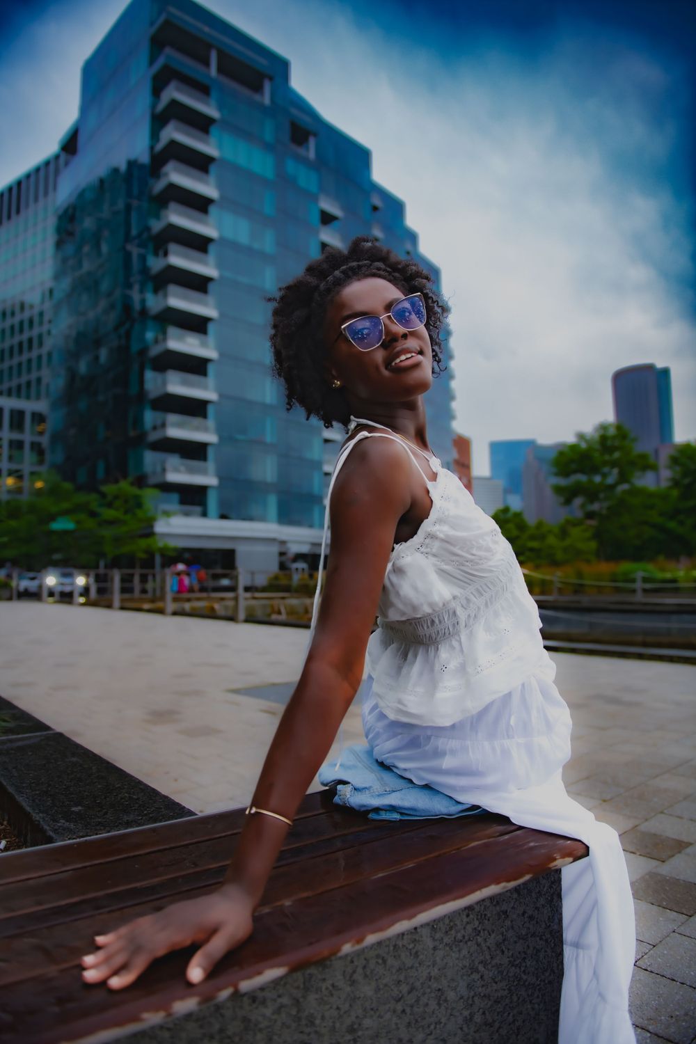 Fashion portrait against modern urban architecture with blue glass building in background.