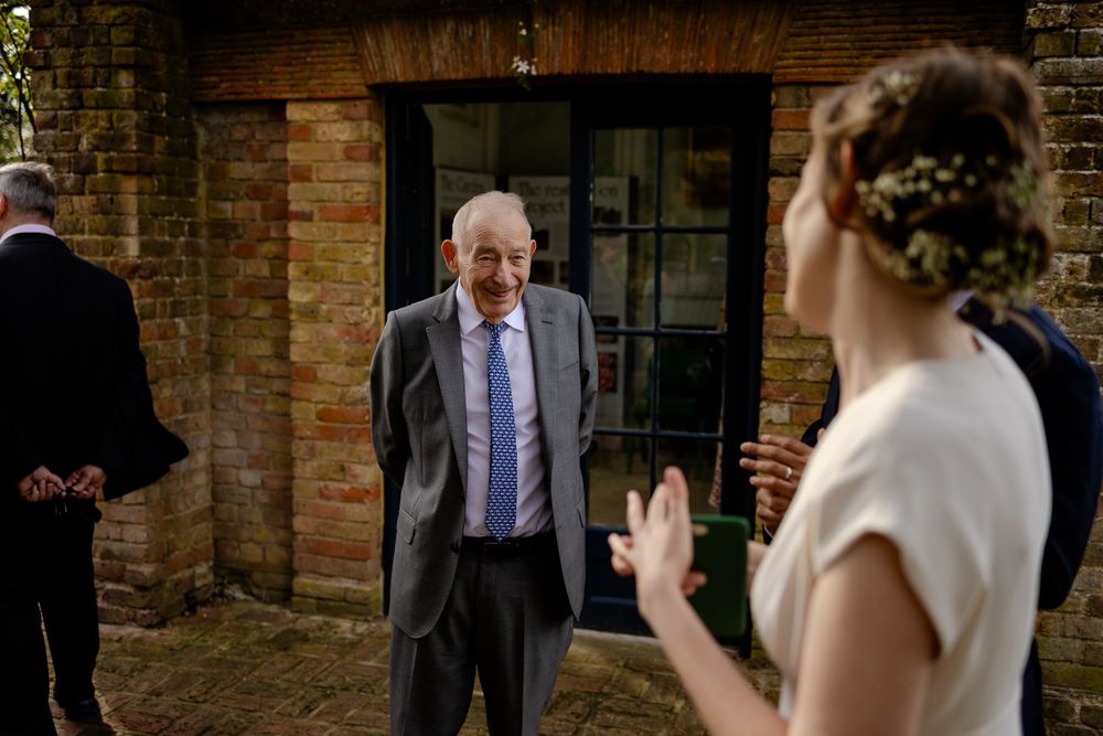 Wedding guest greets others outside brick building during outdoor celebration.
