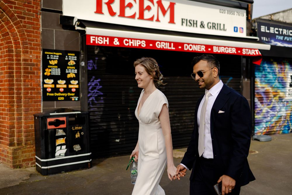 Couple walking past Reem Fish & Grill shop front on urban street.