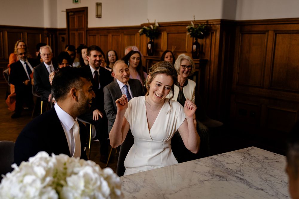 Wedding celebration in wood-paneled room with guests clapping and celebrating.