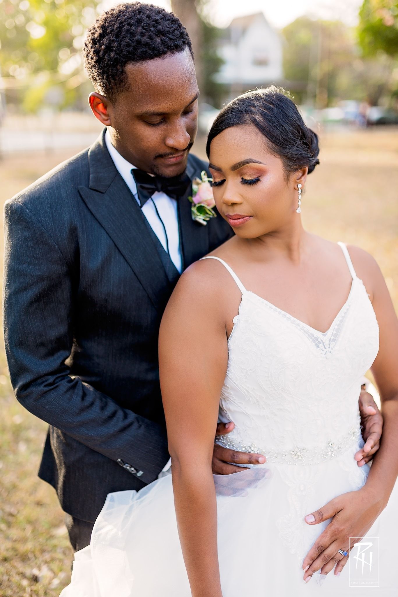 Romantic wedding portrait featuring a couple in formal attire embracing in soft outdoor lighting.