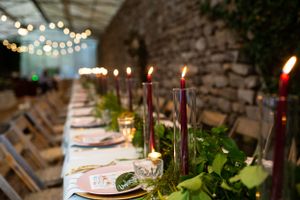 Intimate wedding tablescape with burgundy candles and greenery runners.