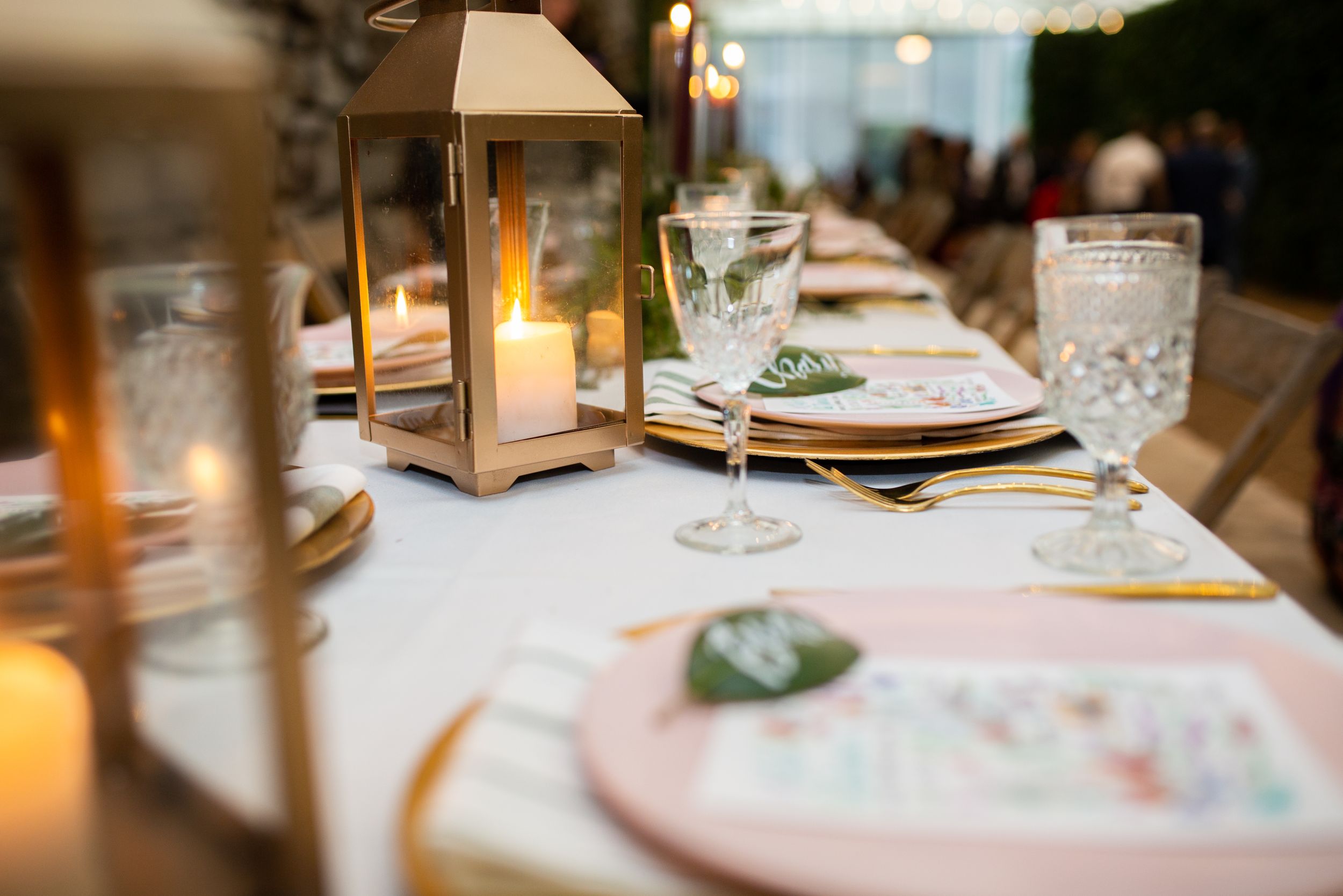 Wedding place setting with lantern centerpiece and crystal glassware.