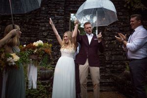 Celebratory moment with clear umbrellas against stone wall backdrop.
