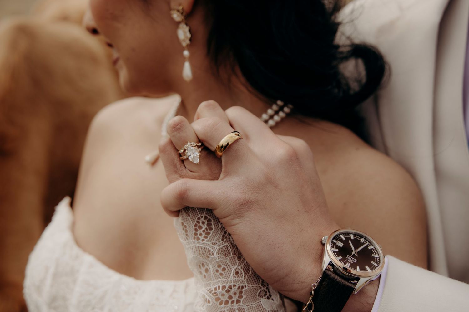 Close-up of bride and groom hands showing wedding rings and a luxury watch.