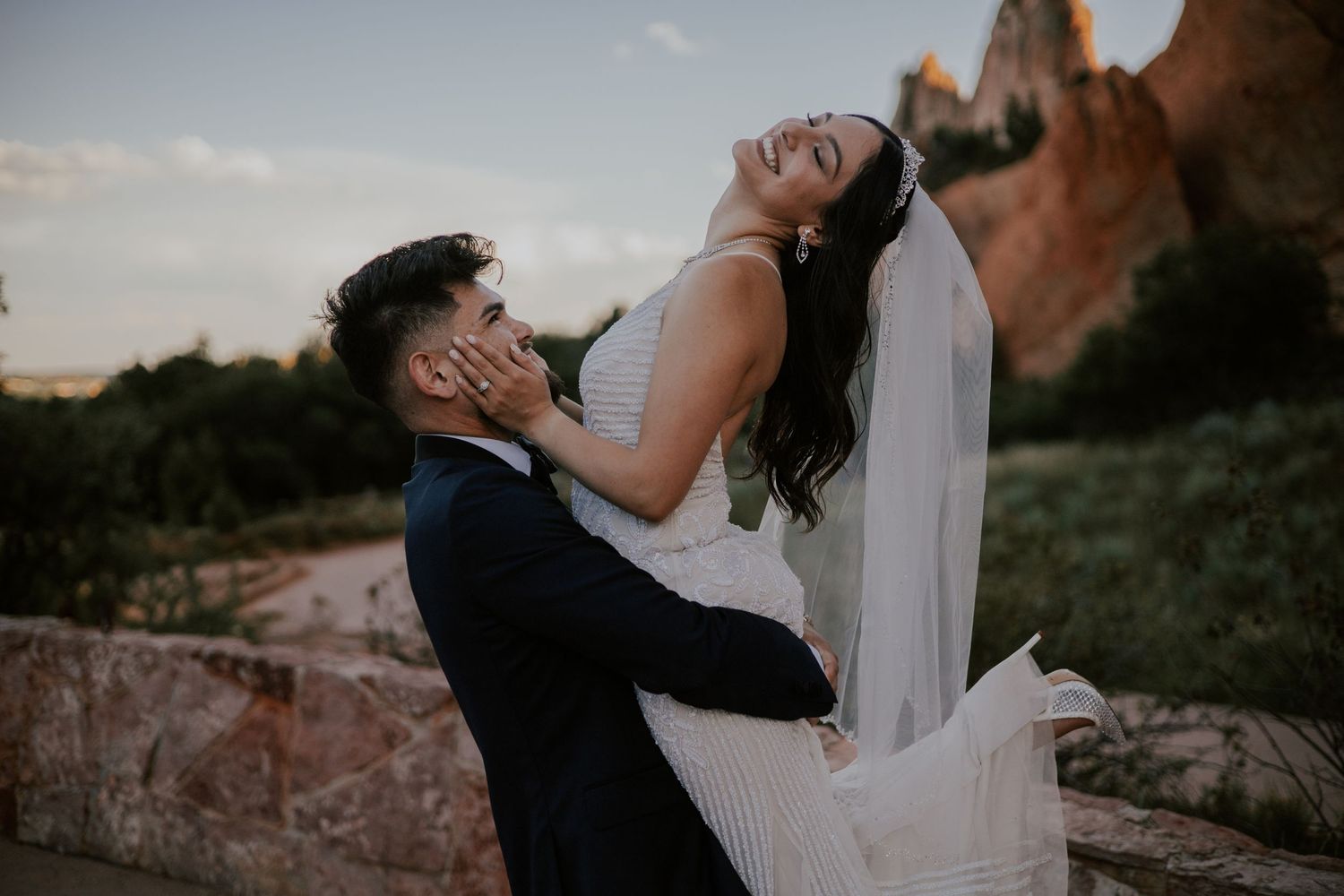Joyful bride laughing as groom holds her at Garden of the Gods red rock wedding venue.