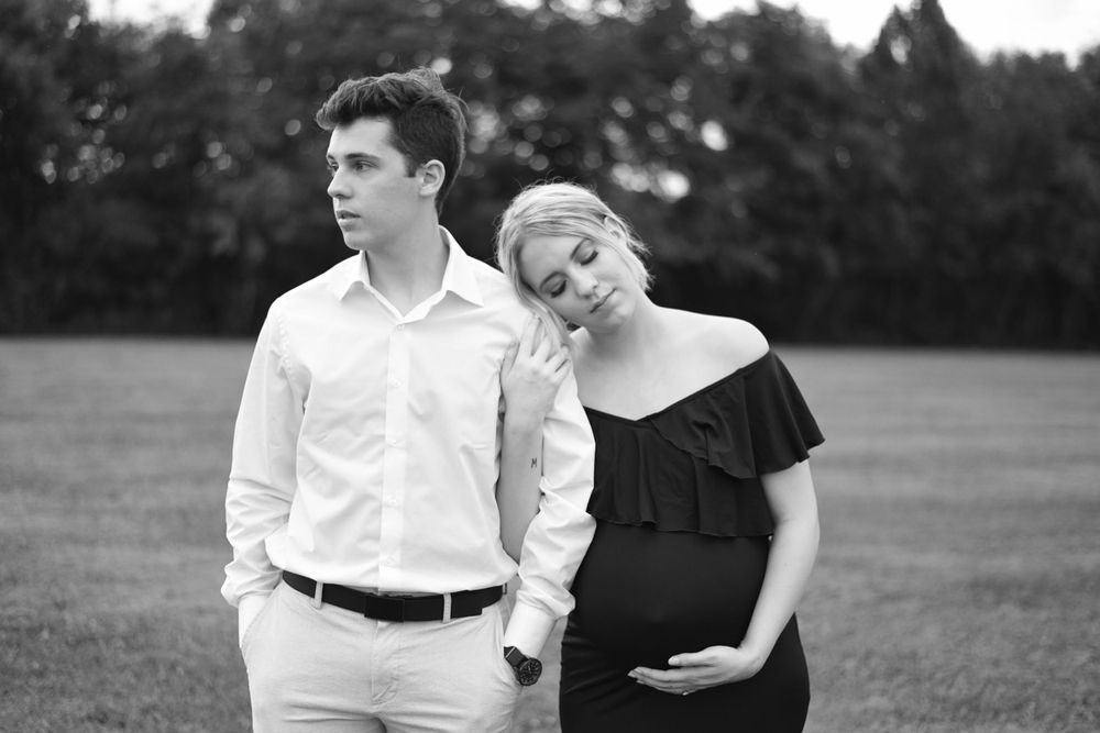 Natural light maternity session showing couple's connection in outdoor setting.