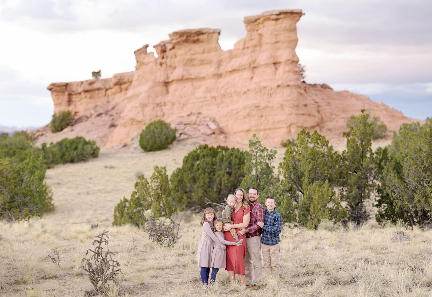 Family portrait in front of distinctive sandstone rock formations in a desert setting.