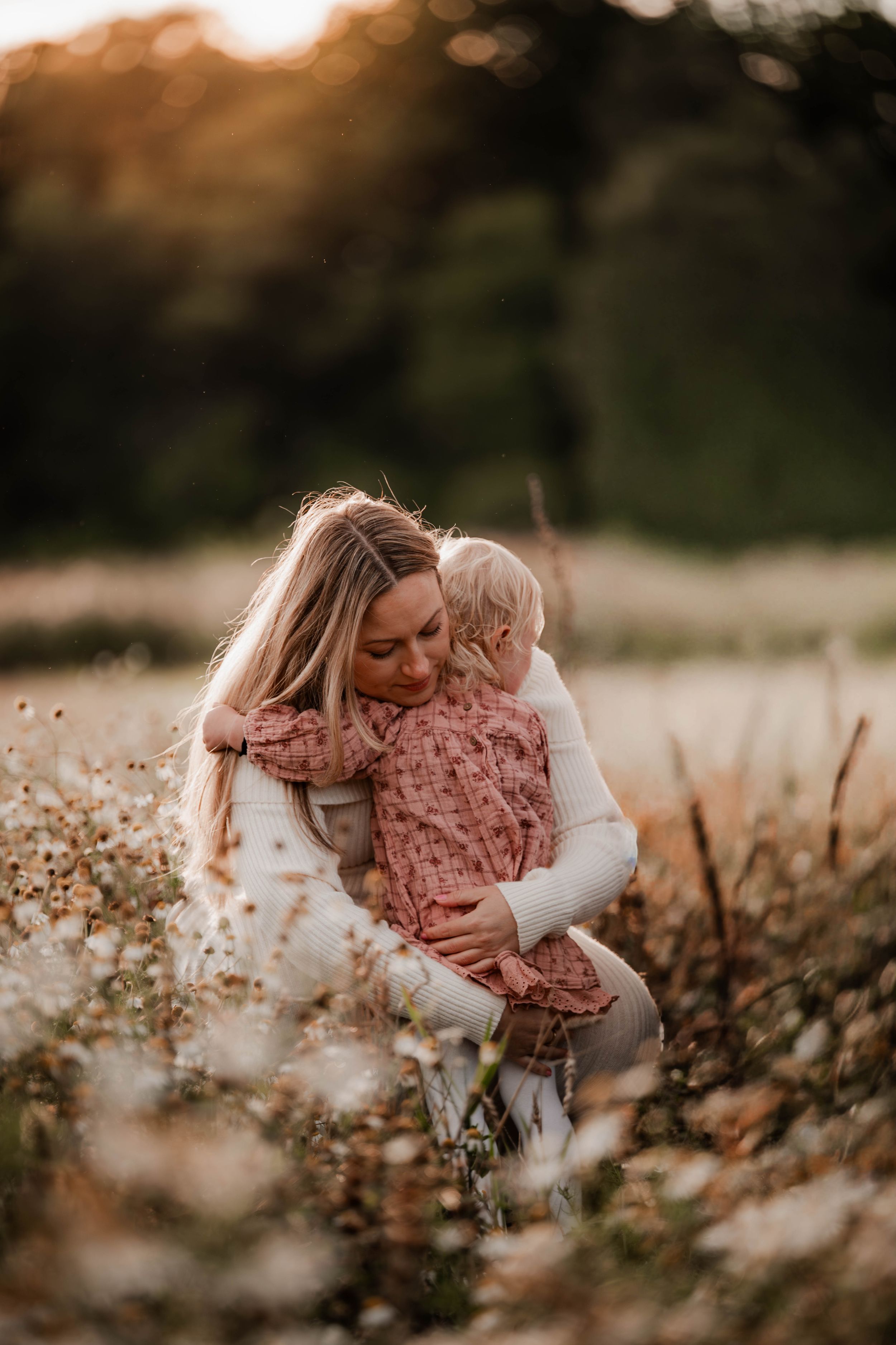Dotter kramar sin mamma bland vita blommor