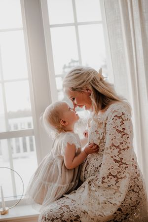 Mamma och dotter inomhus i ett fönster