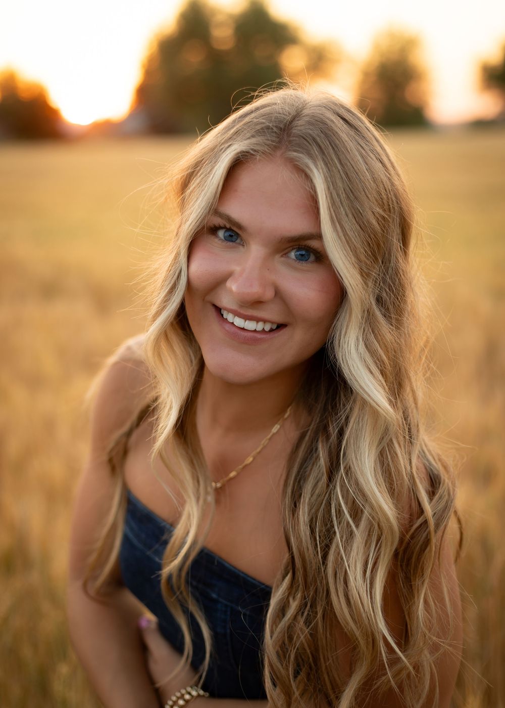 Portrait photograph in a golden wheat field during sunset with soft warm lighting and natural outdoor backdrop.
