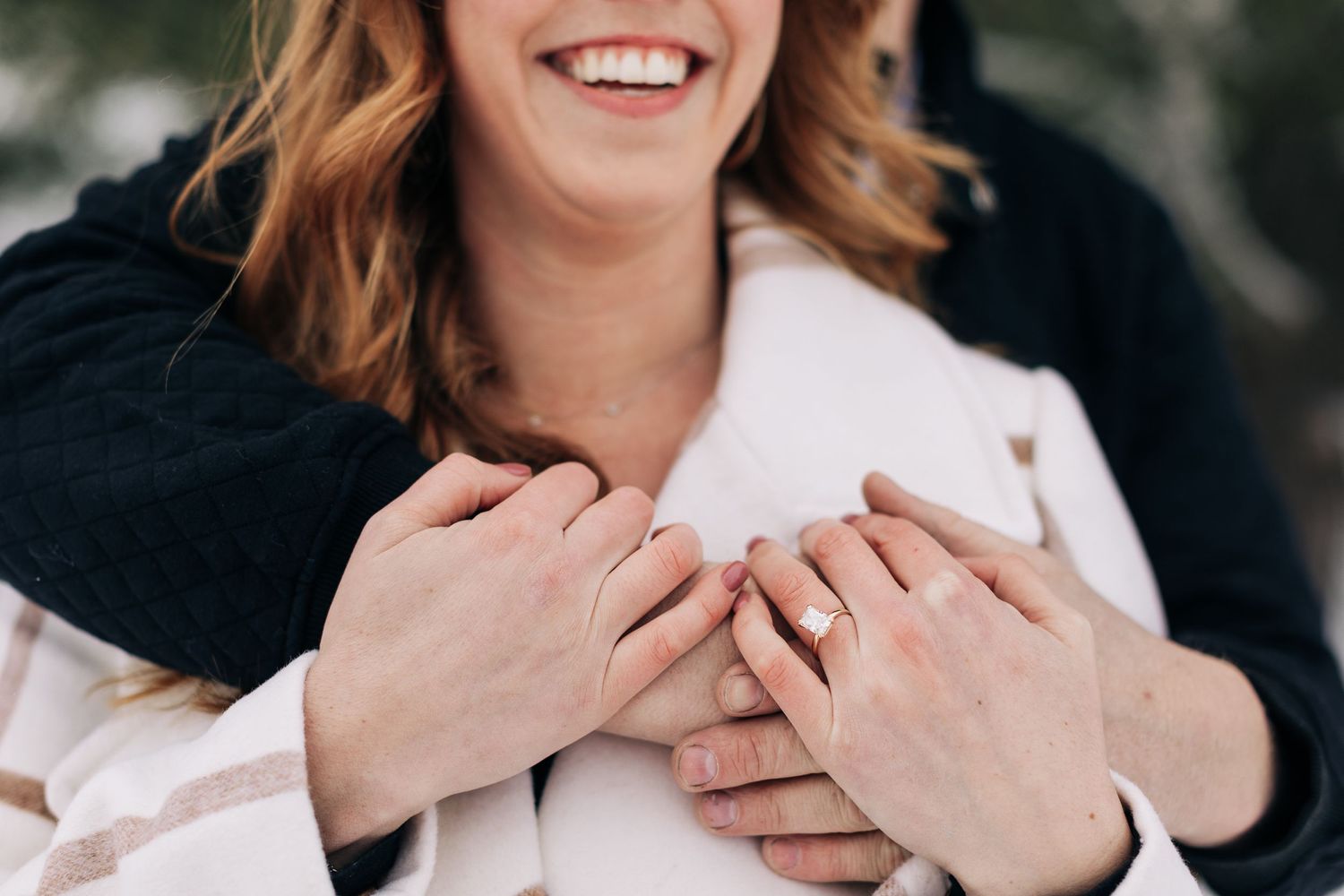 Close-up of hands embracing over white winter coat.