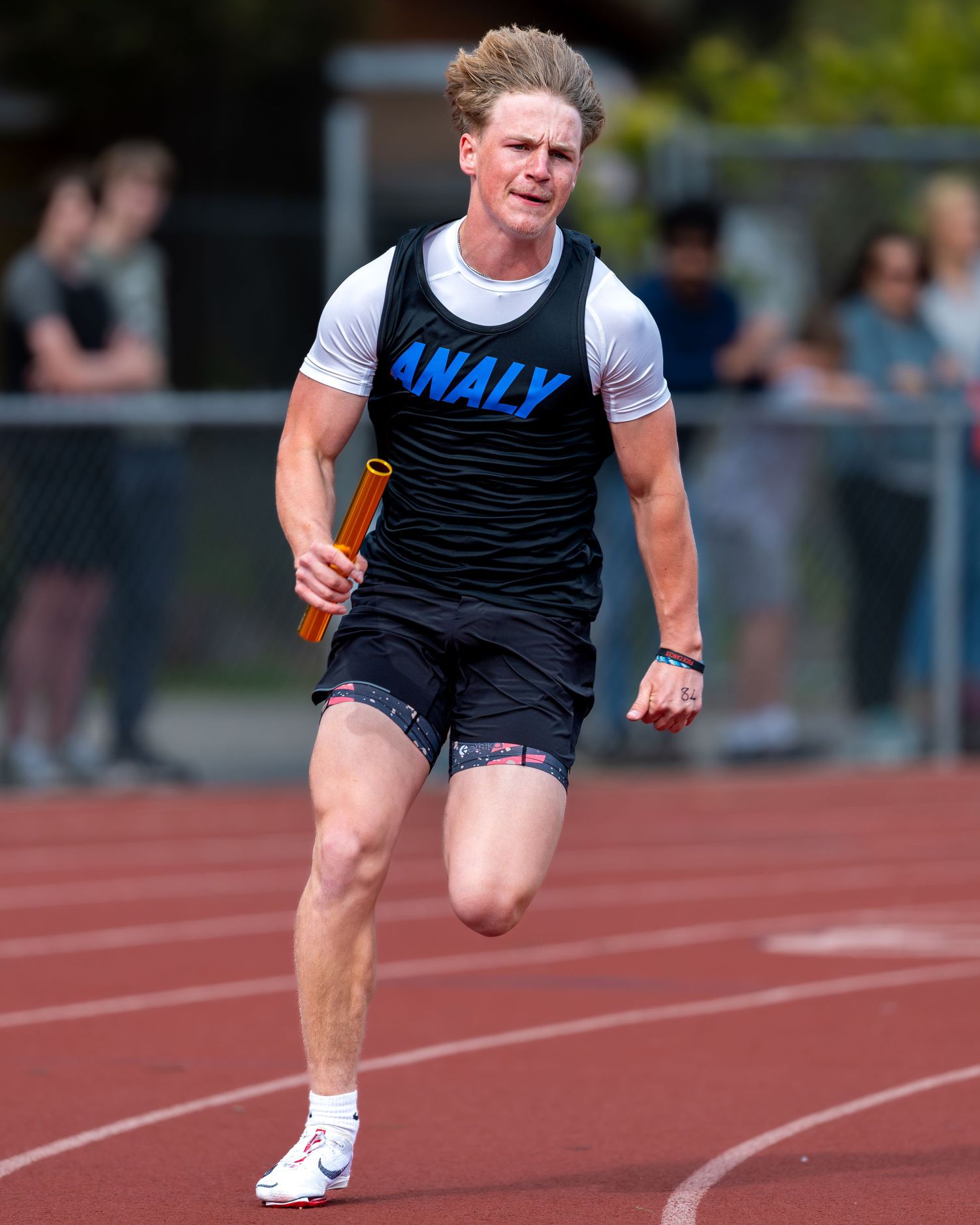 Track athlete in black and blue uniform sprinting on track during competition.