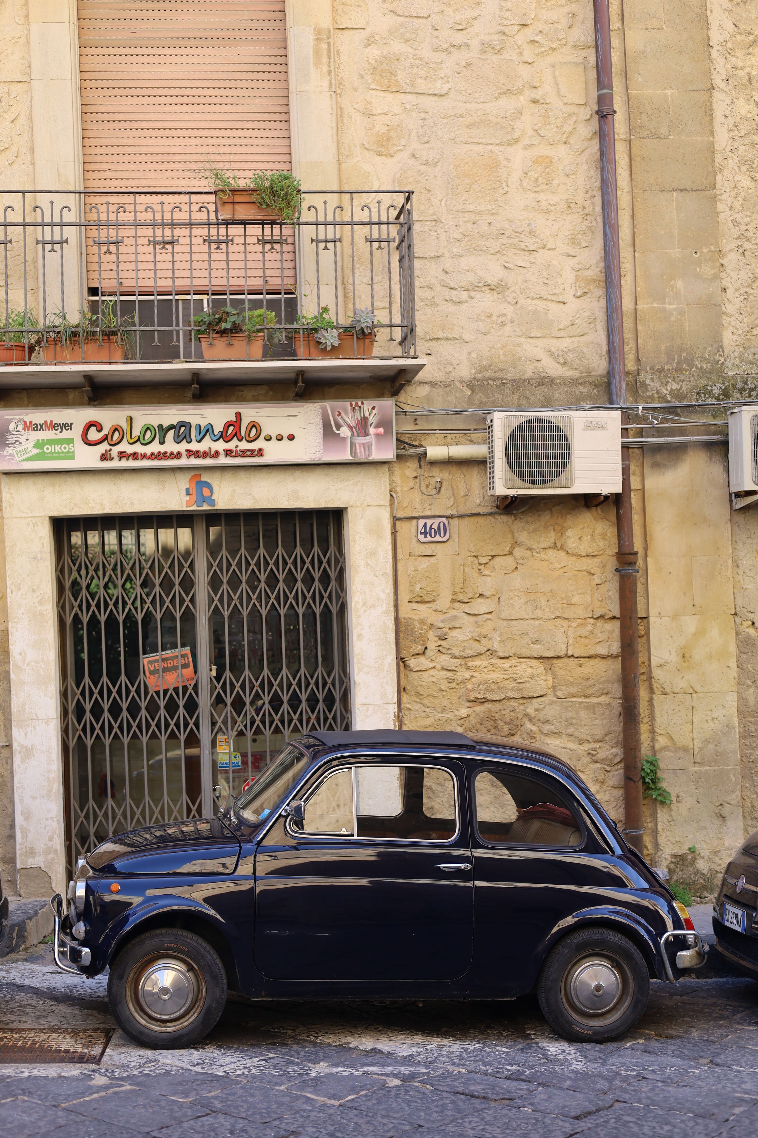 Vintage dark blue Citroën DS parked on a cobblestone street against stone buildings.