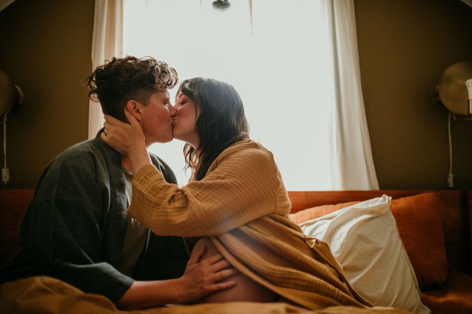 queer couple shares a kiss in bed during documentary maternity photography session portland oregon rushes & waves