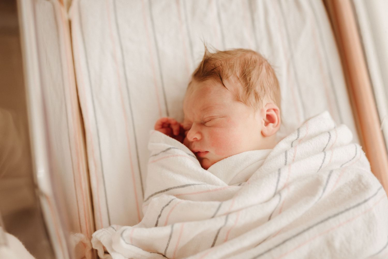 Peaceful newborn sleeping soundly wrapped in white blanket.