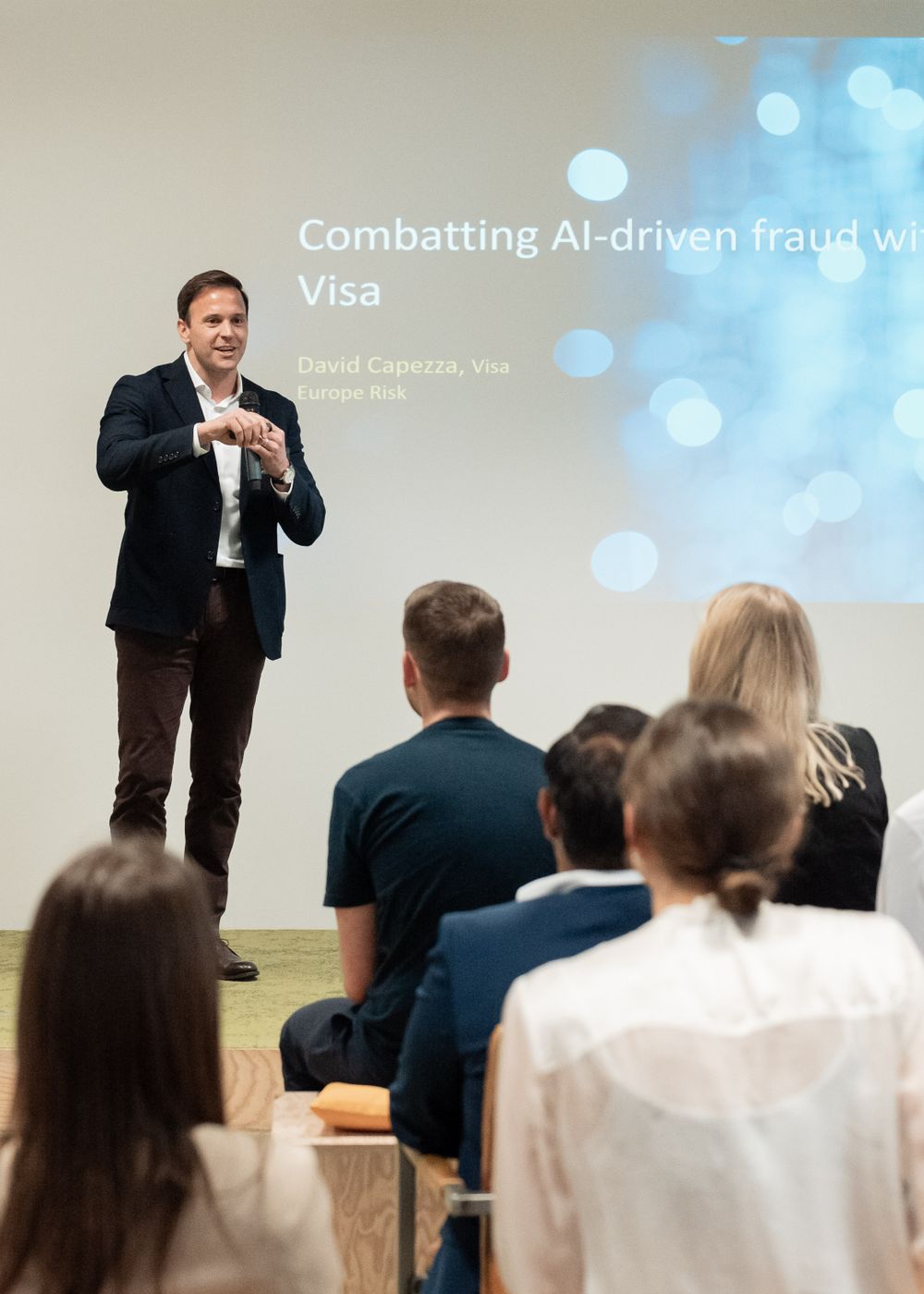 A presentation about AI-driven fraud with Visa shown on a projection screen.
