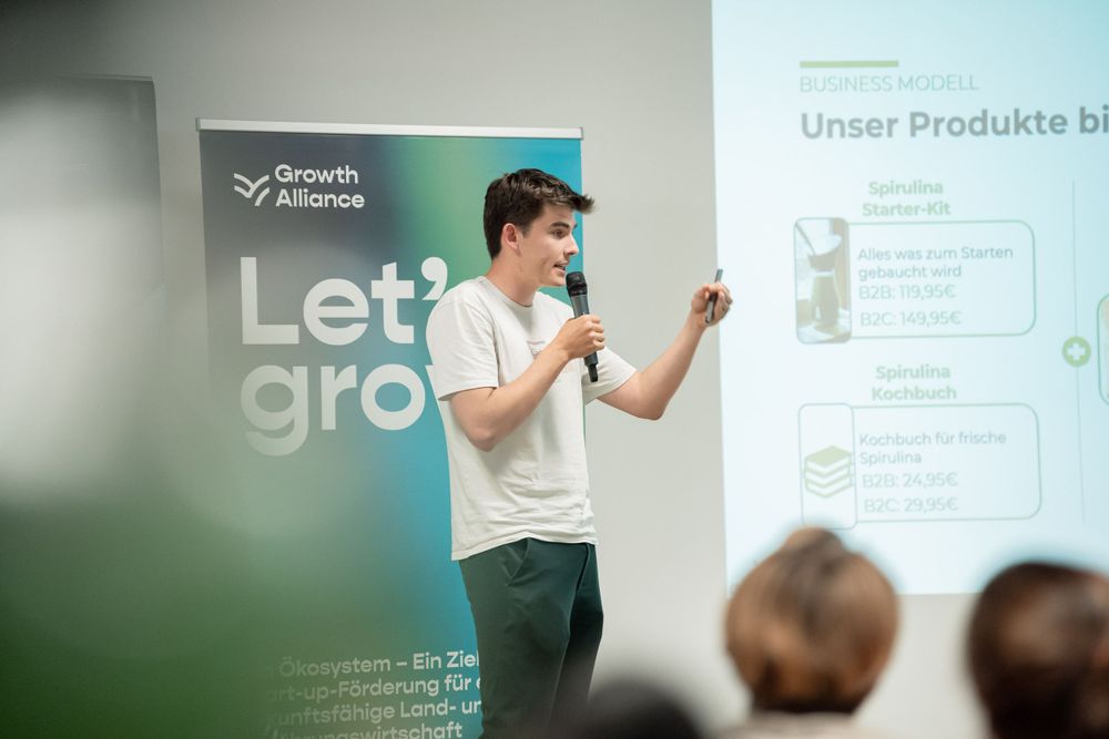Presenter giving a talk in front of 'Let's grow' banner and product slides.