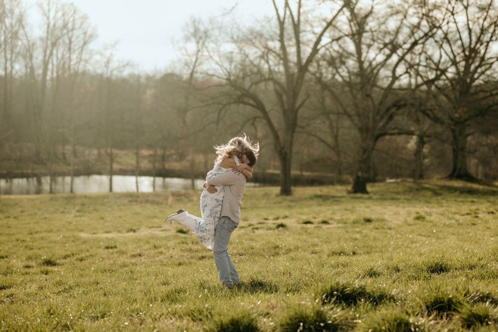 A joyful couple embracing and twirling in a misty field at sunset.