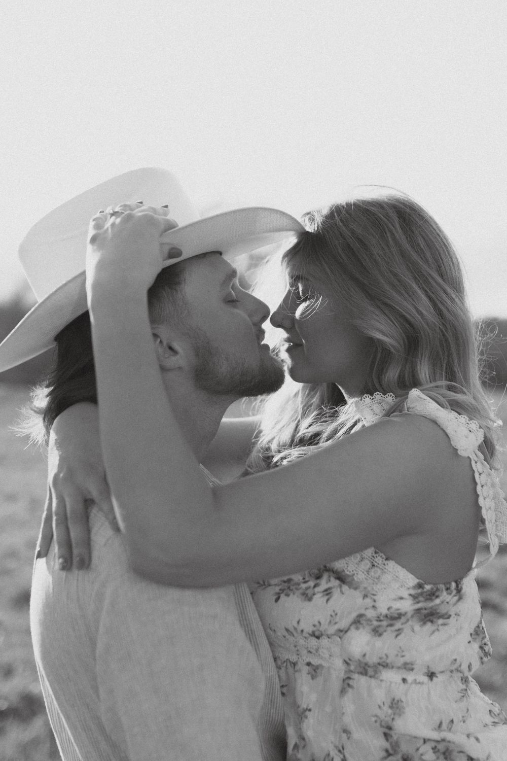 An intimate black and white portrait of a couple sharing a romantic moment in western wear.