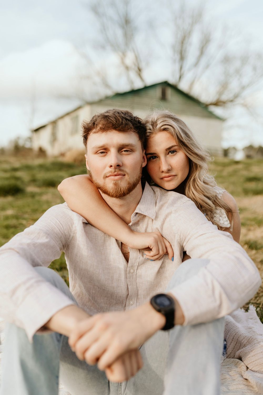 A tender embrace captured in front of a rustic barn in warm evening light.