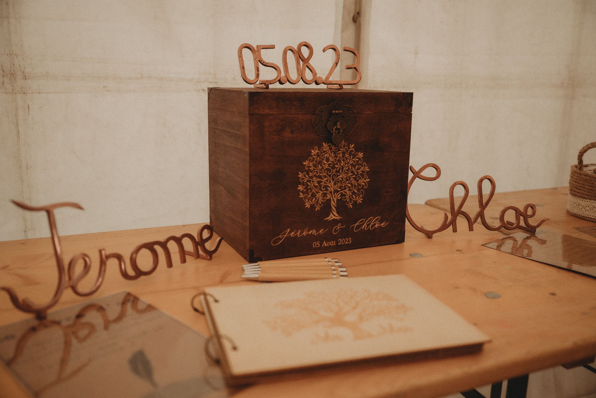 A wooden box with a tree design and cursive names Jerome and Chloe on a rustic table.