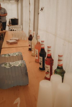 A row of colorful liquor bottles lined up on a wooden table with gray boxes.