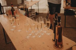 Champagne glasses and wine bottles arranged on a wooden table at an event.